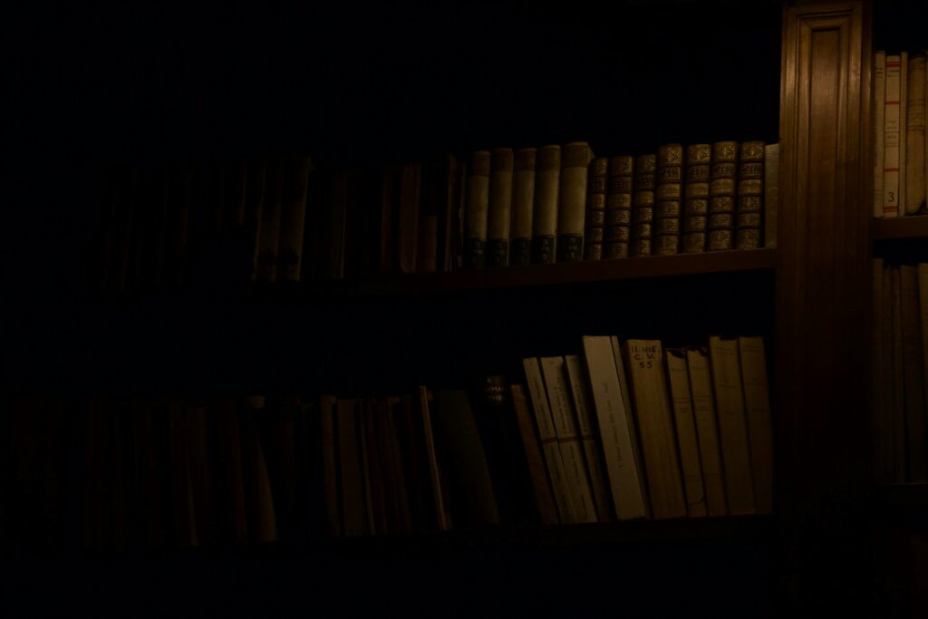 a bookshelf filled with lots of books in a dark room