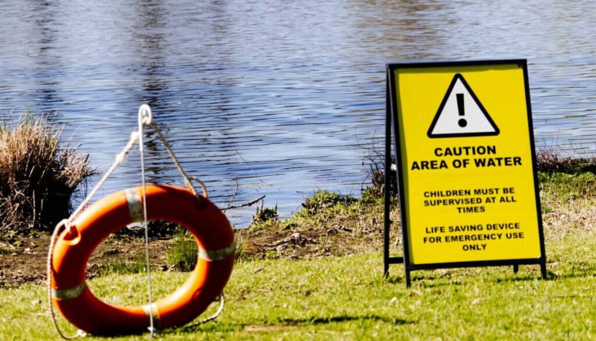 Life preserver and caution sign near water